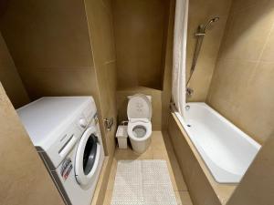 a small bathroom with a toilet and a washing machine at Branz BSD Apartment 2BR in Samporo