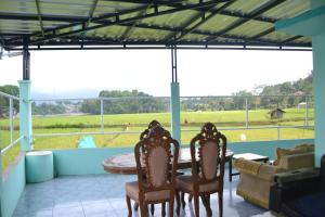 a porch with chairs and a table and a couch at PanjaluNet Homestay in Panjalu