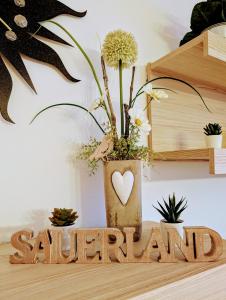 a wooden sign with a vase with a plant at Ferienwohnung Jansen in Kirchhundem
