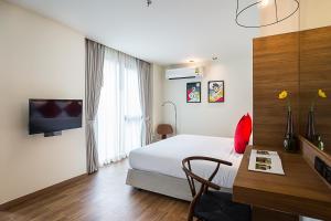 a hotel room with a bed and a desk and a tv at Sunshine Hip Hotel in Pattaya