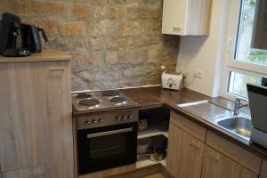 a kitchen with a stove and a stone wall at Ferienhaus Lisbeth in Edesheim +10 photos