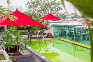 a pool with two red umbrellas and a building at Sunshine Hip Hotel in Pattaya