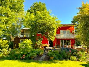 a red house with a garden in front of it at Atelier Seeshaupt ruhige Oase zwischen den Seen in Seeshaupt