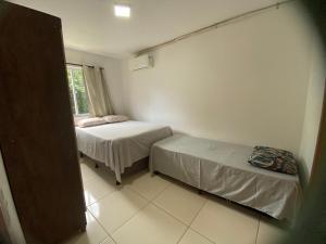 een kleine kamer met twee bedden en een raam bij Apartamento Vog Atlântico in Ilhéus +8 foto's
