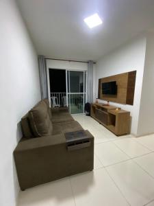 een woonkamer met een bank en een televisie bij Apartamento Vog Atlântico in Ilhéus
