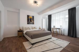 a white bedroom with a bed and a table at Pop Up Aparthotel in Bucharest