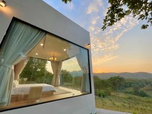 a bedroom with a large window with a view at Rabbit Forest สวนผึ้ง in Thung Faek