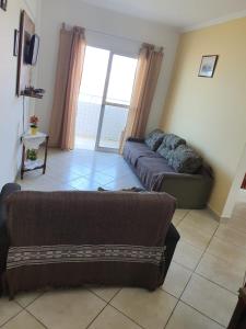 a living room with a couch and a large window at Ap frente pro mar bloco - 2 in Mongaguá