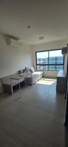 a living room with a couch and a large window at Grene Donmueng in Thung Si Kan