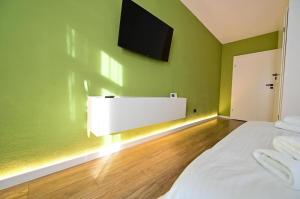 Un dormitorio con una cama blanca y un televisor de pantalla plana. en Old Town Ruby, en Sibiu