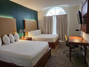 a hotel room with two beds and a desk and a window at Montreal Suites Orlando in Orlando