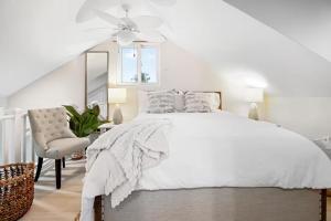 una camera da letto bianca con un letto e una sedia di NEW LUXE Caribbean Cottage in THE BAHAMAS with Canal Access! a Nassau Altre 42 foto