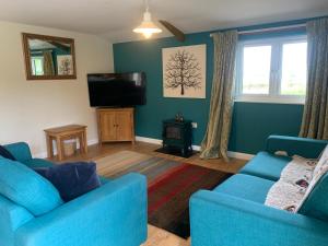 a living room with two blue couches and a television at Field End in Liskeard