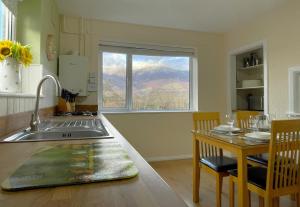 a kitchen with a sink and a table and a window at Roslin in Portinscale
