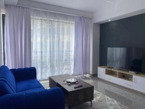 a living room with a blue couch and a large television at Sapphire in Nairobi