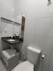 a bathroom with a toilet and a sink and a mirror at Casa Serena - Quarto in Camocim +12 photos