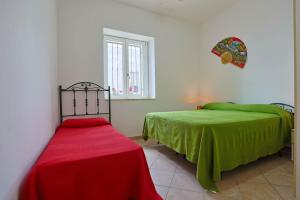 a bedroom with two beds with green sheets and a window at Casa Laura 2 a soli 20 mt dalla spiaggia di San Pietro in Bevagna in San Pietro in Bevagna