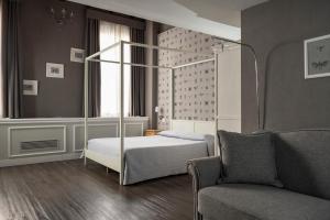 a bedroom with a bed and a chair and a couch at Maxxim Hotel & Loft in Ferrara +100 photos