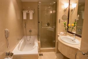 Un baño con bañera, lavabo y ducha. en Premium Strato Hotel, en Doha
