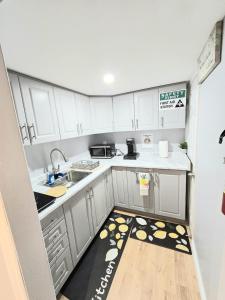 a kitchen with white cabinets and a wooden floor at Welcome to your Serene Gateway in London +16 photos