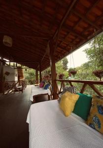 a room with two beds and a porch with tables at Casa Muiraquitã Experiências Amazônicas in Santarém
