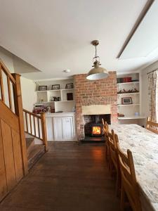 a dining room with a table and a fireplace at Willow Cottage in Longney