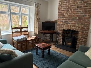 a living room with a brick fireplace and a tv at Willow Cottage in Longney