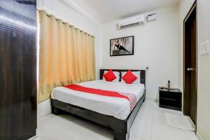 a bedroom with a bed with red pillows at Hotel O Manu Residency in Bangalore +53 photos
