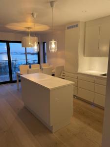 una cucina con mobili bianchi, tavolo e sedie di Exclusive apartment in Kristiansand - Høllen a Kristiansand Altre 22 foto