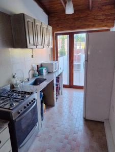 a kitchen with a stove and a sink and a refrigerator at Chalet PA La Perla MAR DEL EDÉN in Mar del Plata +8 photos