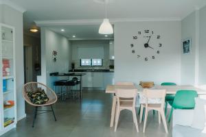 a dining room with a table and chairs and a clock at Comfort Zone beach apartment in Quarteira +39 photos