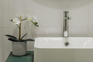 a white sink with a vase with white flowers in it at Comfort Zone beach apartment in Quarteira +38 photos