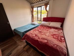 ein Schlafzimmer mit einem Bett mit einer roten Decke und einem Fenster in der Unterkunft El Refugio de Paipa Lugar de Descanso y Tranquilidad in Paipa