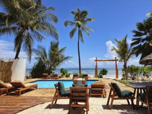 a resort with a pool and chairs and palm trees at HA Beach Boutique - Adults Only in Jambiani