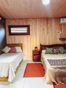 a bedroom with two beds and a red rug at Bossa Kite House in Cumbuco