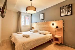 a bedroom with a large bed with a wooden headboard at Résidence les Chardons - maeva Home - Appartement chaleureux 4 pièces 8 personnes - Prestige - super Home MAE-3341 in Arc 1800