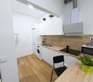 a kitchen with white cabinets and a table and a sink at Anna Home in Telde