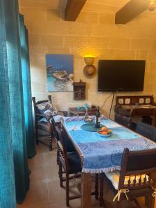 jadalnia ze stołem i telewizorem w obiekcie Gozo Sunset Holiday Accomodation w mieście Qala