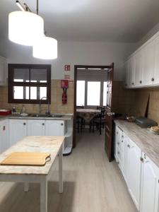 une cuisine avec des armoires blanches et une table à l'intérieur dans l'établissement Casa Dona Teresa, à Santa Cruz