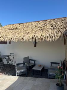 a straw roofed patio with chairs and tables at LA PAILLOTE D OR in Sainte-Anne