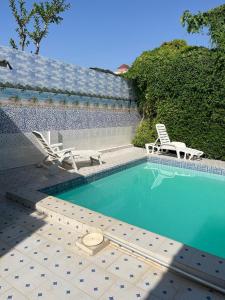 - une piscine avec 2 chaises longues et 2 chaises dans l'établissement Jummaneh Studio Apartment, à Brusubi
