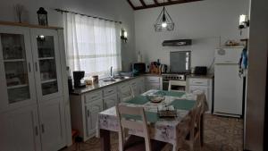 a kitchen with white cabinets and a table and a sink at Quinta da Baldaia in Rabo de Peixe