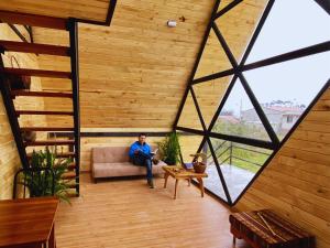 Hacienda OpoteChasky Glamping的坐在一张沙发上的人,坐在一个大窗户的房间