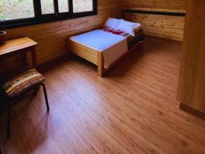 a small bedroom with a bed and a wooden floor at Chasky Glamping in Hacienda Opote