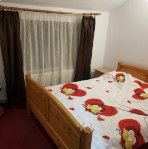 a bedroom with a bed with red flowers on it at Apartament Casa cu Flori de Munte in Buşteni