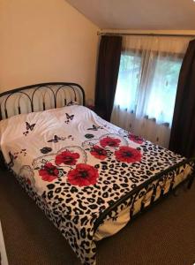 a bed with a black and white blanket with red flowers at Apartament Casa cu Flori de Munte in Buşteni +1 photo