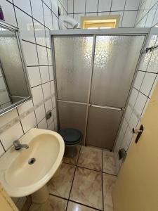 a bathroom with a sink and a shower with a toilet at Chalé Condomínio Vila Suiça - Balneário Rincão in Vila Nova +13 photos