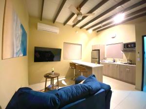 a living room with a blue couch and a kitchen at Aruba IXORA Suites in Noord