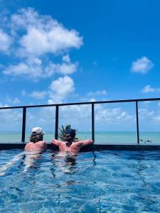 zwei Personen in einem Pool mit Meerblick in der Unterkunft Bless Hospedagem Flat beira mar de Cabo Branco in João Pessoa