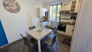a kitchen with a table and chairs and a clock at La Luziole 3 étoiles, en vacances ou cure, été ou hiver, comme chez vous in Luz-Saint-Sauveur
